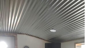 A living room with a sofa, a coffee table, and a ceiling with a ribbed design.