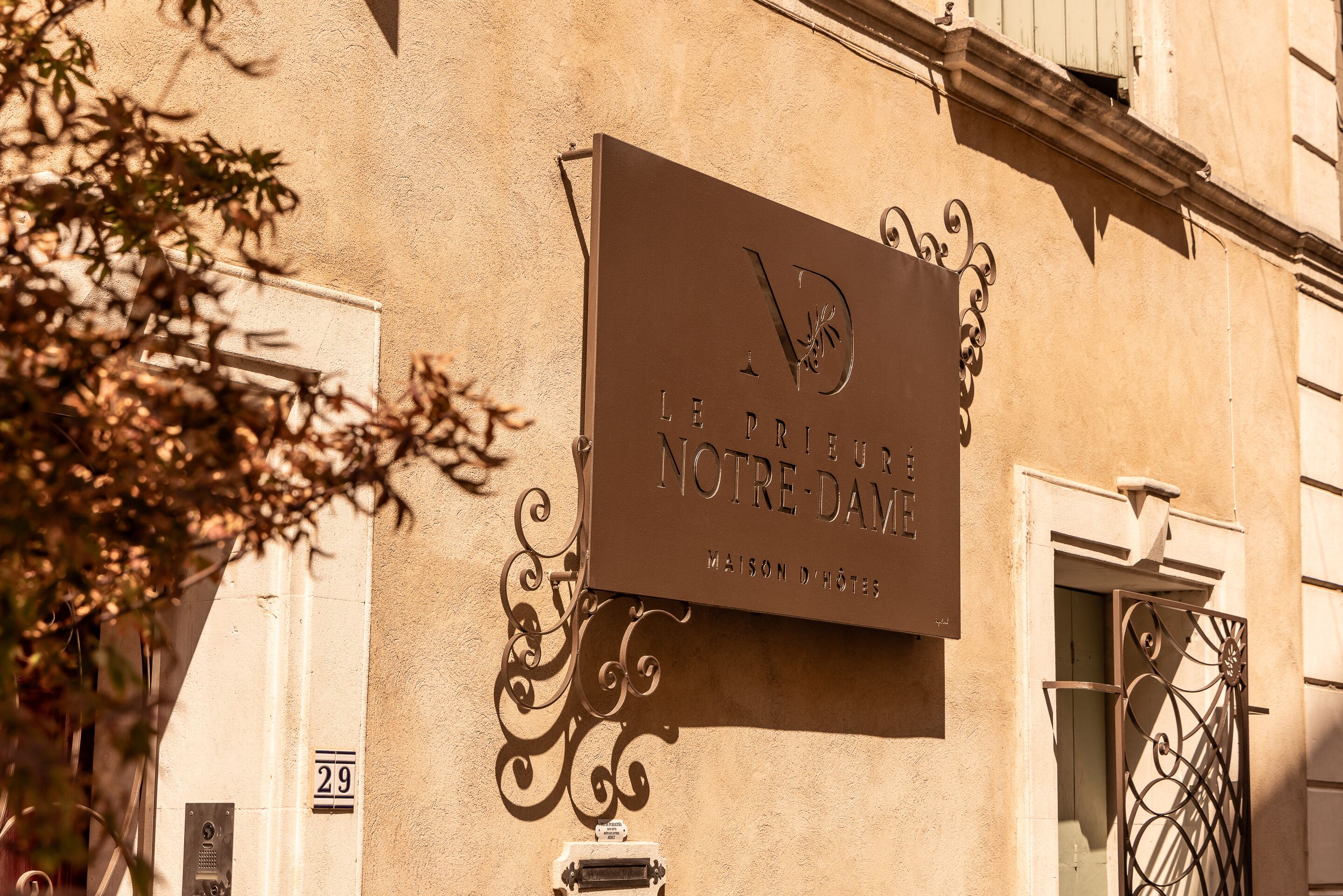 A sign for "Le Prieuré Notre-Dame" with a number "29" on the building.