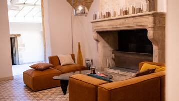 Una sala de estar con chimenea, dos sofás, una mesa de centro y una lámpara colgante.