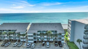 Ein Strandhotel mit mehreren Balkonen, einem Parkplatz und Meerblick.