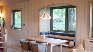 A cozy room with a wooden dining table, wicker chairs, a bench with cushions, and a hanging light fixture. - Luxury Treehouse with amazing views in 100 acres of secluded private Land. (Hereford)