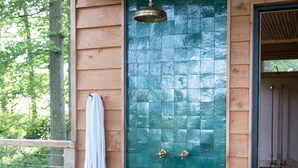 A wooden door with a green mosaic pattern, a towel hanging on the left, and a wooden deck with a bench. - Luxury Treehouse with amazing views in 100 acres of secluded private Land. (Hereford)