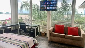 Ein Zimmer mit einem Bett, einem Schreibtisch, einer Couch und einem an der Wand befestigten Fernseher.