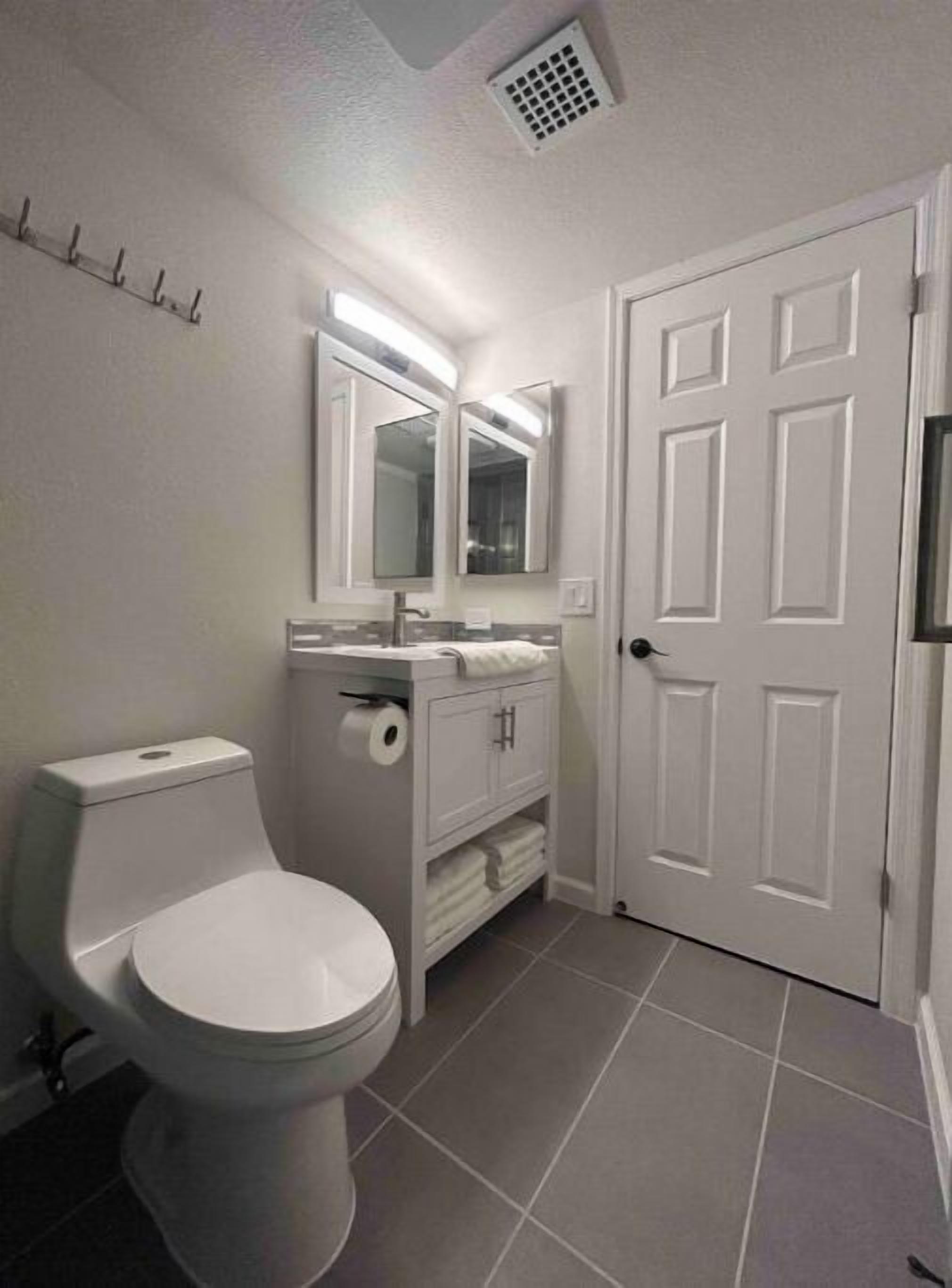 Et badeværelse med toilet, vask og spejl.