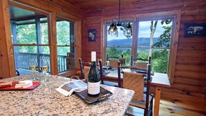 Houten cabin interieur met een granieten tafel, wijnglazen, een fles wijn en uitzicht op de omgeving.