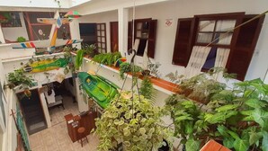 Een meerlaagse ruimte binnenshuis met verschillende planten, een groene kajak en een hangende decoratie.