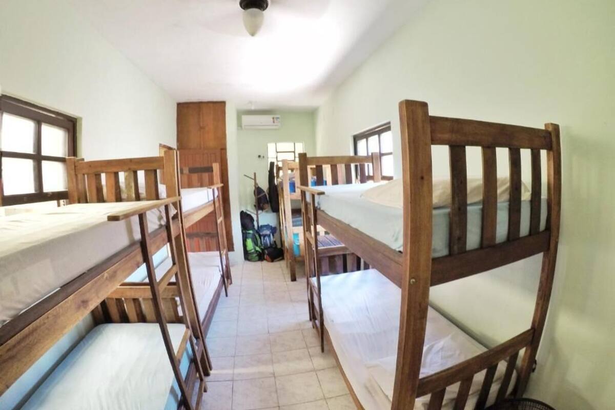 Une chambre de dortoir avec des lits superposés, un ventilateur de plafond et une fenêtre.