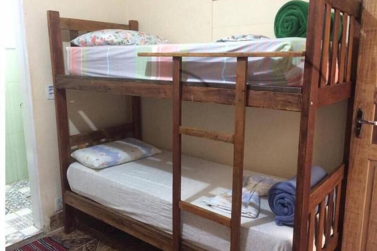 Un lit superposé avec une structure en bois, un matelas et un oreiller.