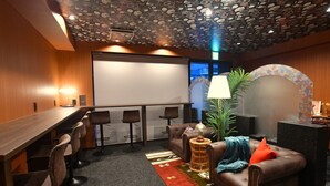 A conference room with a long table, four bar stools, a brown leather sofa, a patterned rug, and a ceiling with a fruit and flower design. - FORBELL STAY YURIGAOKA (Kawasaki)