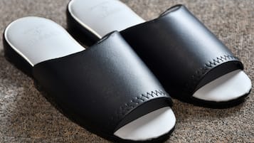 Ett par svarta sandaler med vita sulor och ett sicksackmönster på sidan, placerade på en strukturerad yta.