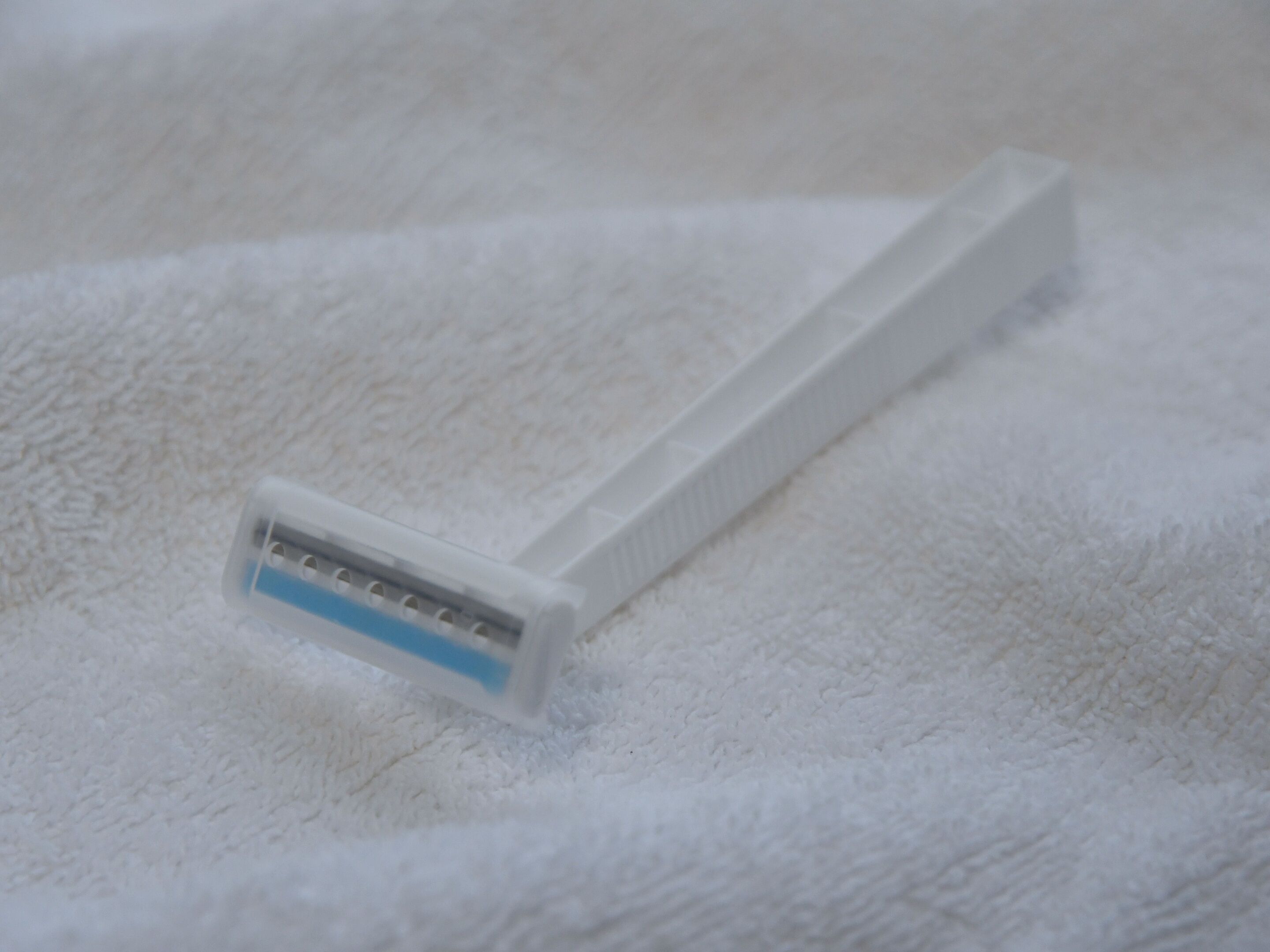 A white razor on a white towel.