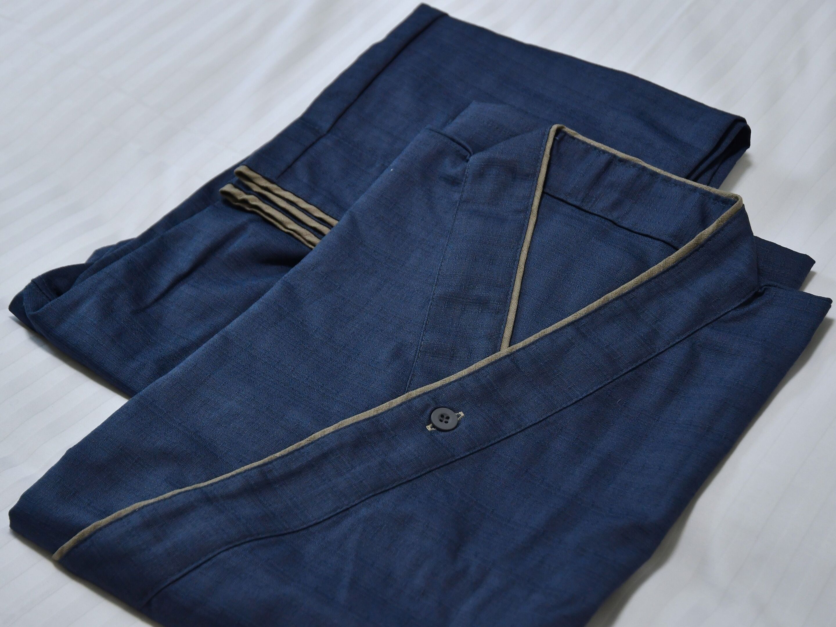 A neatly folded blue garment with a button and a collar.