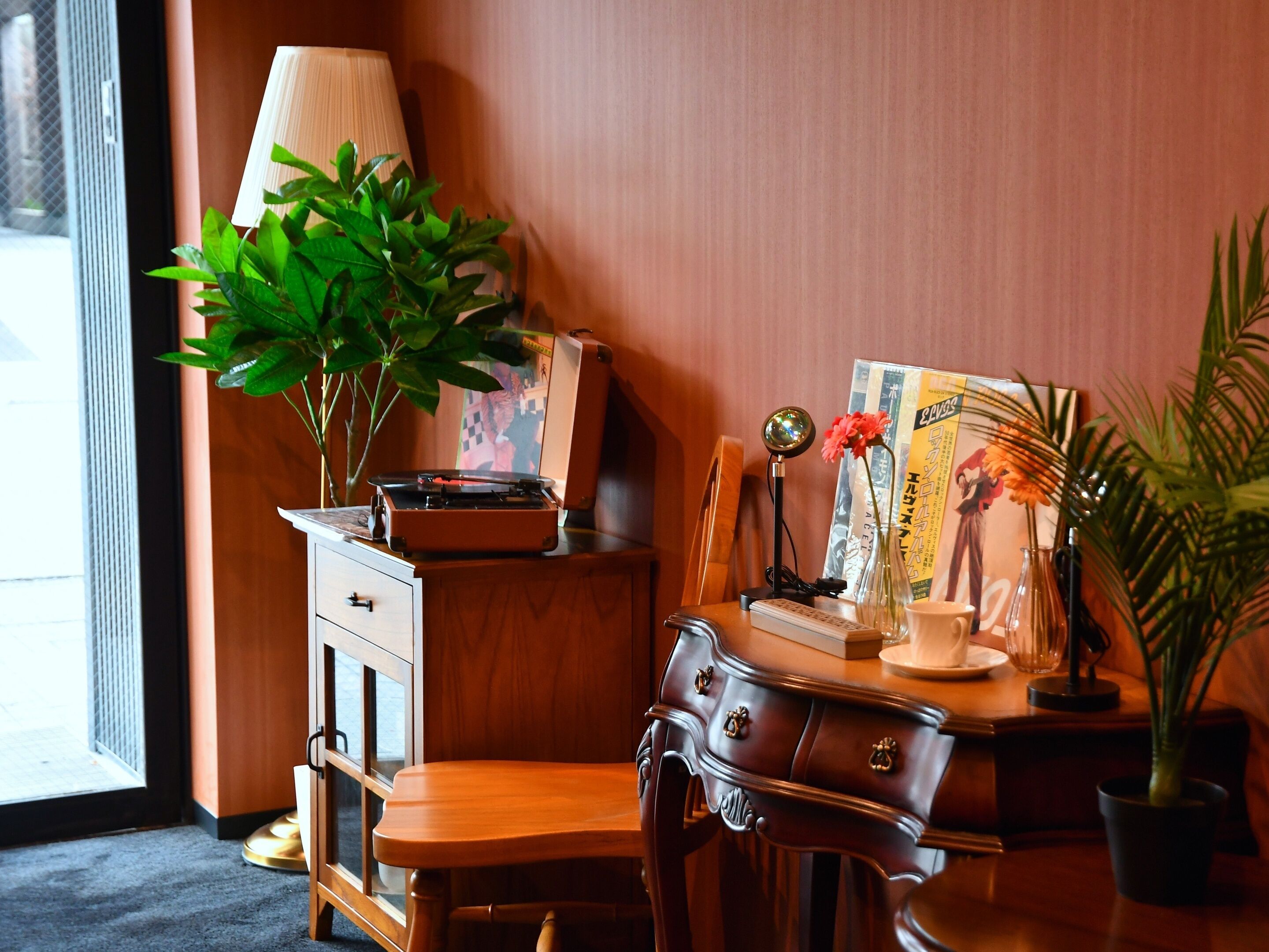 A cozy room with a wooden desk, a lamp, a plant, and a vintage radio.