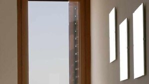 Ein Zimmer mit Fenster, einem Tisch mit Lampe und einem Sofa.
