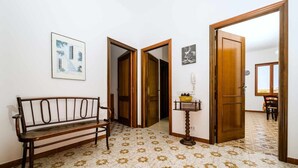 Ein Flur mit einer Bank, gemusterten Bodenfliesen, Holztüren und einem kleinen Tisch mit einer Vase.