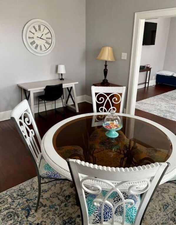 A dining area with a round glass table, white chairs with blue patterns, a wall clock, and a lamp. - 1.5 blocks to beach. Close to cruise terminal. Safe neighborhood. Spacious 1/1 (Galveston)