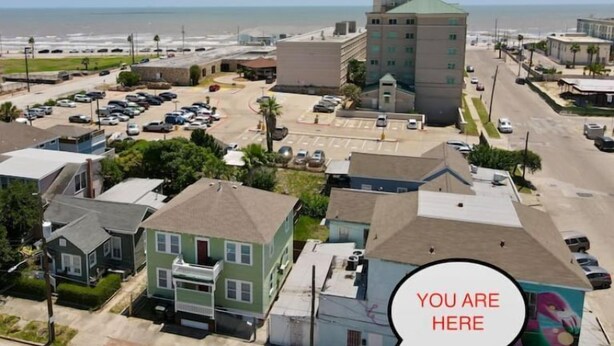 An aerial view of a coastal town with a prominent hotel building, parking lots, and residential houses. - 1.5 blocks to beach. Close to cruise terminal. Safe neighborhood. Spacious 1/1 (Galveston)