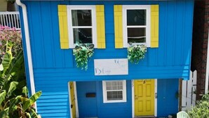 Un bâtiment à deux étages avec une façade bleue, des volets jaunes et une enseigne sur laquelle on peut lire « Blue Bungalow ».