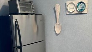 Une cuisine avec un réfrigérateur en acier inoxydable, une cuillère en bois et un petit objet décoratif accroché au mur.