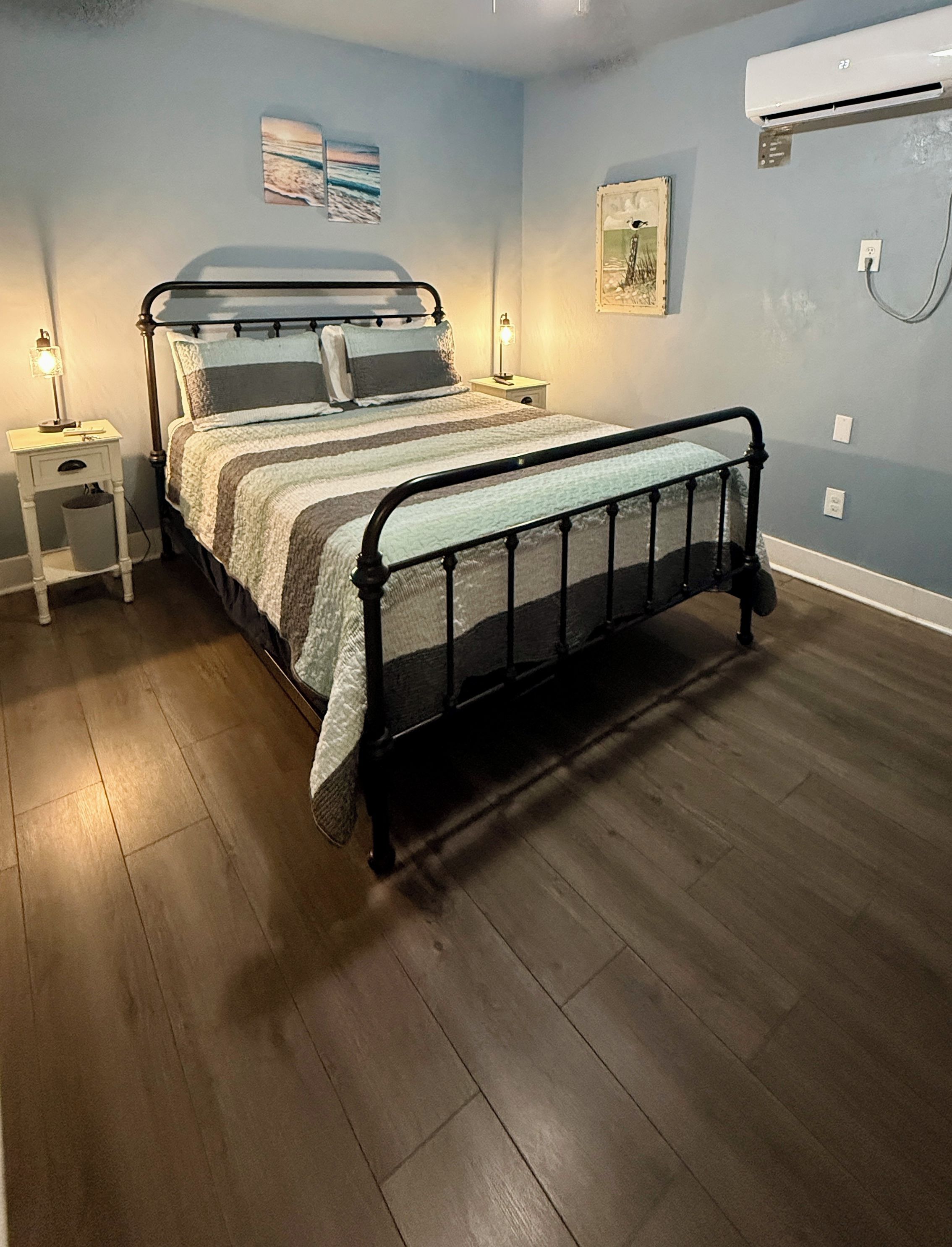 A bedroom with a bed, nightstands, and wall-mounted air conditioning.