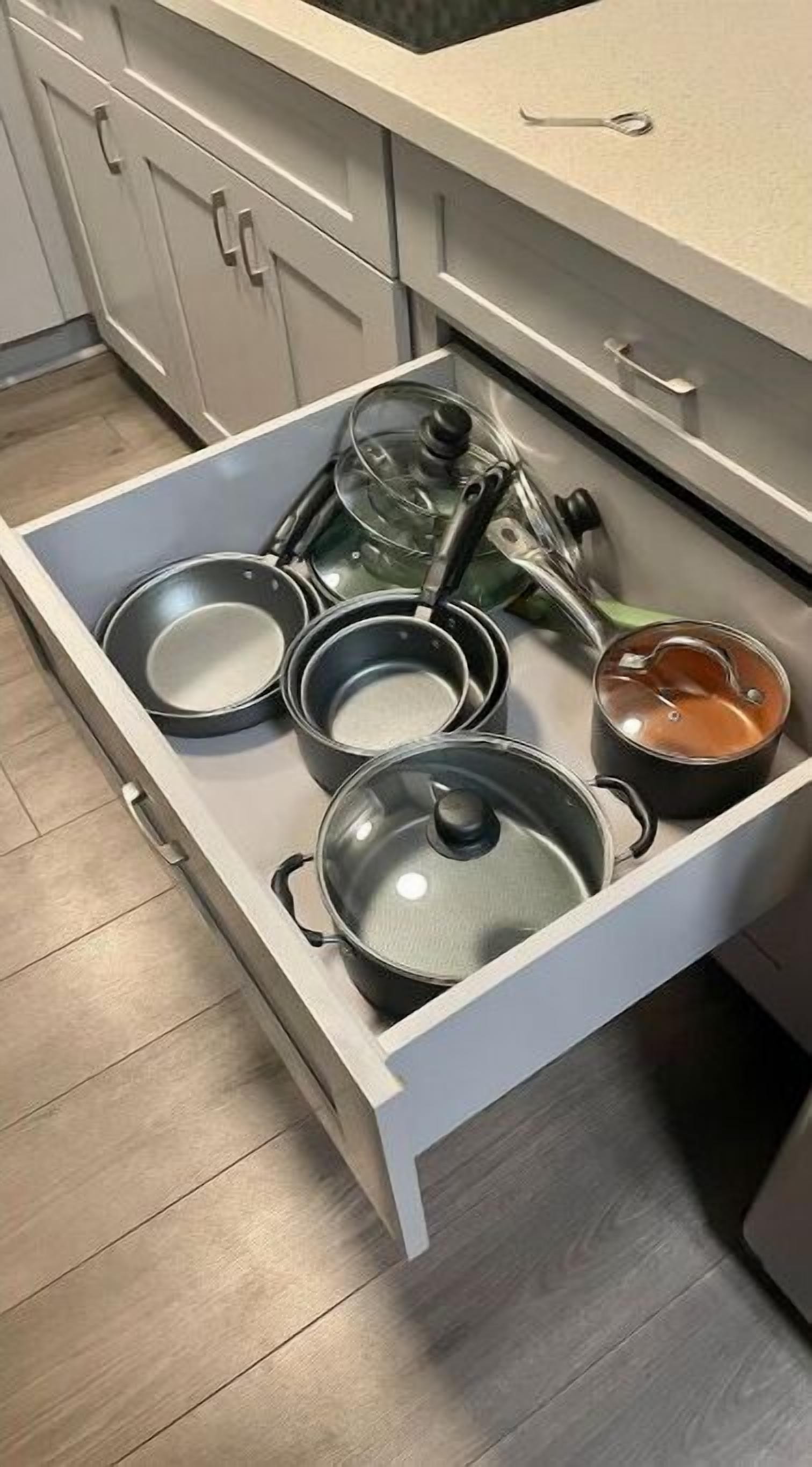 A kitchen drawer with various pots and pans.