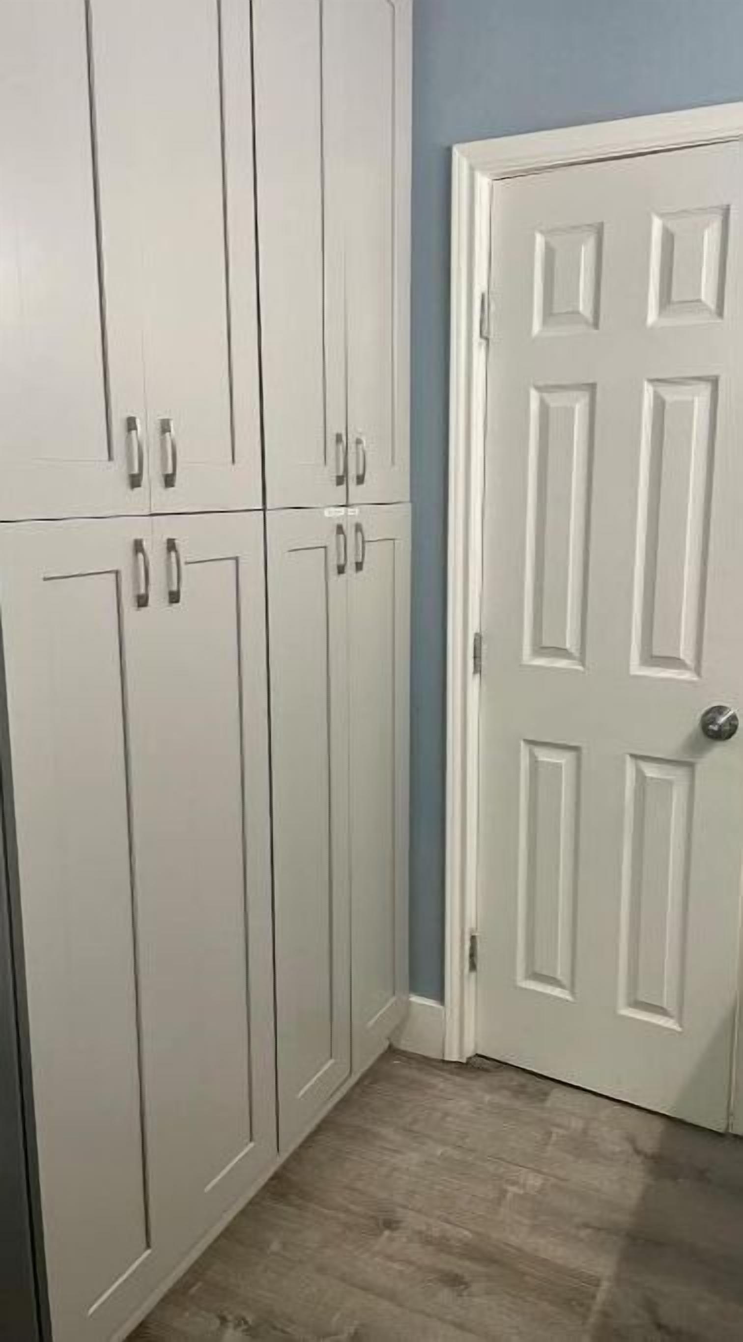 Un couloir avec des portes doubles blanches et une armoire dotée de poignées argentées.