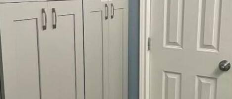 Un couloir avec des portes doubles blanches et une armoire dotée de poignées argentées.