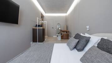 Een moderne hotelkamer met een groot bed, een flatscreen televisie aan de muur, een klein bureau met stoel, een spiegel en een ronde tafel met een vaas.