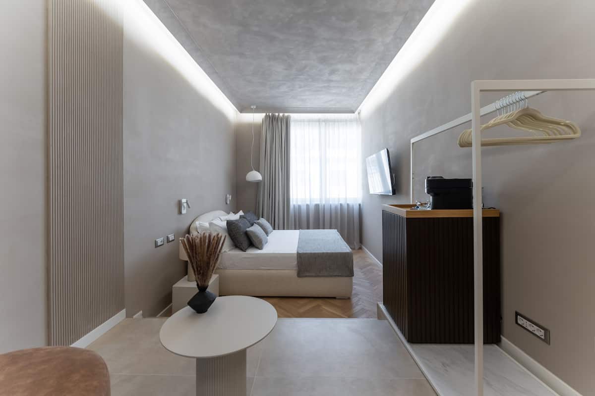 A modern bedroom with a bed, bedside table, and a mirror.