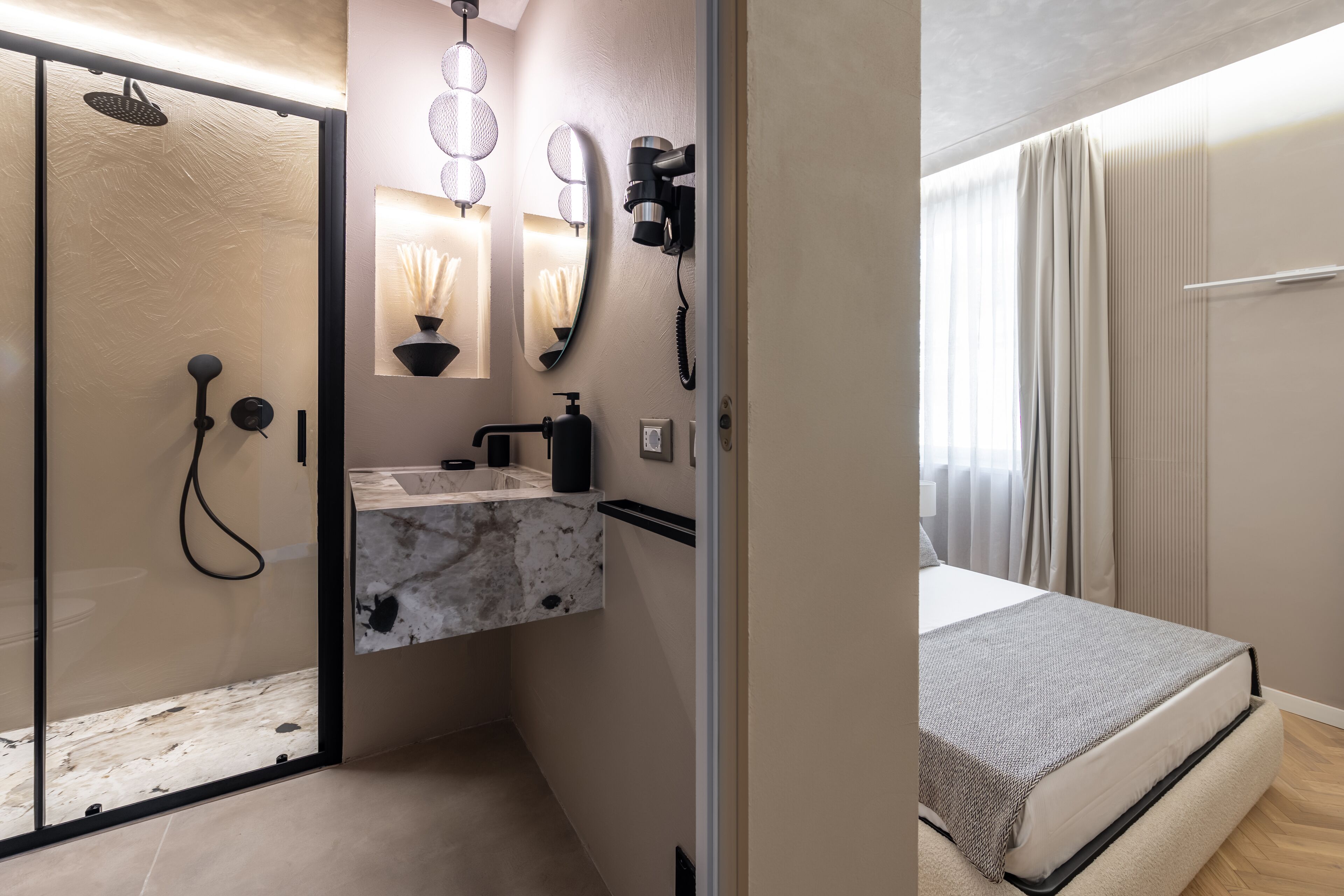 Un baño moderno con cabina de ducha de vidrio, tocador de mármol y secador de pelo instalado en la pared.