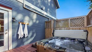 Un bain à remous avec une terrasse en bois et une maison en arrière-plan.