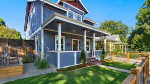 Une maison à deux étages avec un porche, un petit jardin et une clôture en bois.