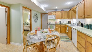 A kitchen with wooden cabinets, a dining table set for four, and a microwave above it. - Fort Calhoun Home w/ Screened Porch + Playground! (Fort Calhoun)