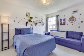Una camera da letto con un letto, un divano, una finestra e decorazioni alle pareti.