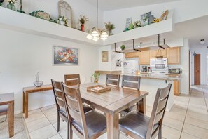 Un coin repas avec une table et des chaises en bois, une cuisine avec des meubles de rangement en bois et un luminaire au plafond.