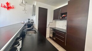 Una cocina moderna con encimera negra, electrodomésticos de acero inoxidable y armarios de madera oscura.