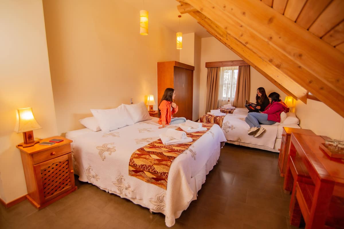A cozy bedroom with two beds, wooden headboard, and bedside lamps.