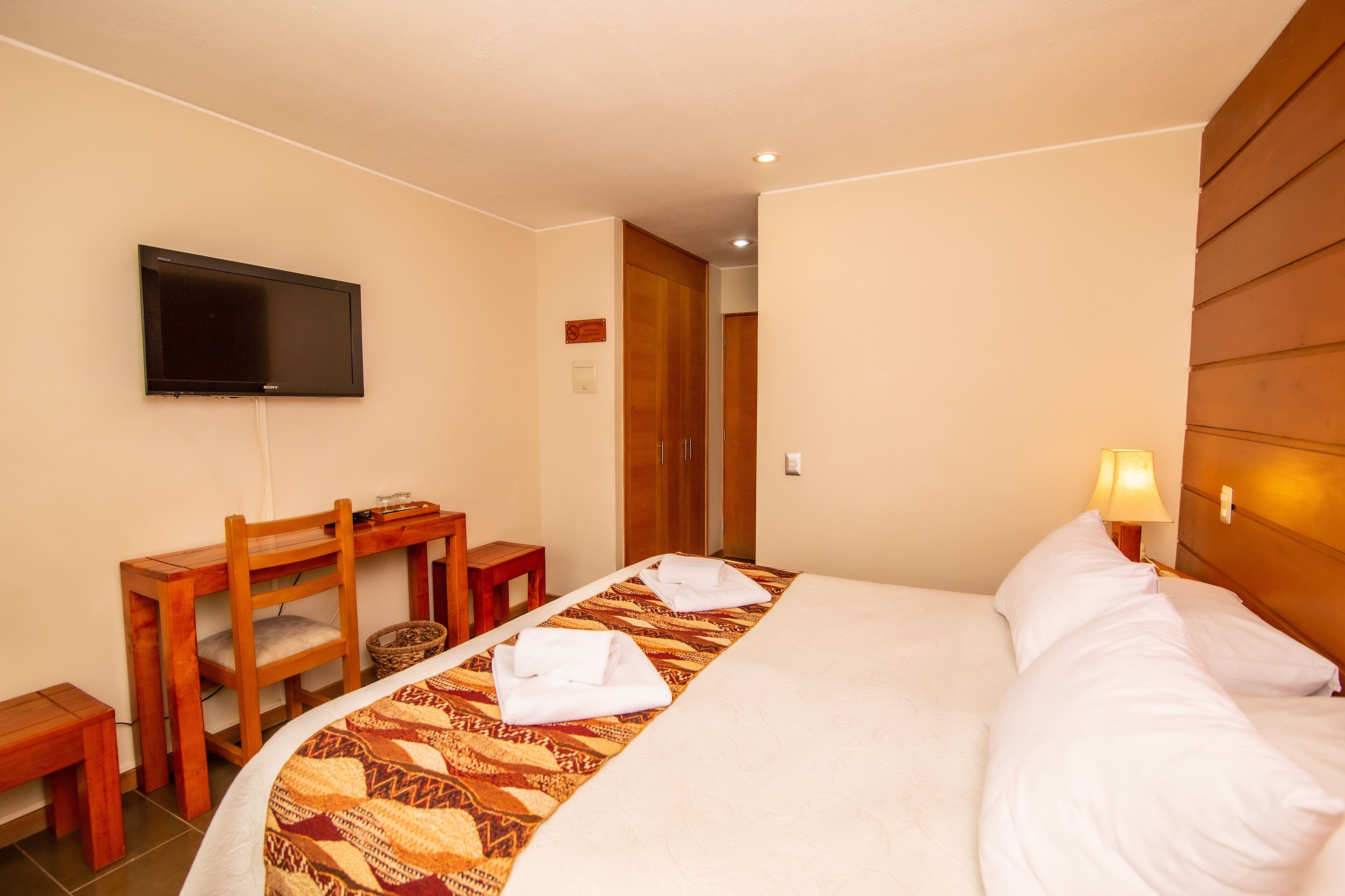 Ein Hotelzimmer mit einem Bett, einem Schreibtisch, einem Sessel, einem Fernseher und einer Lampe.