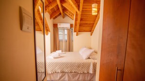 A bedroom with a wooden ceiling, a bed with white bedding, and a window with curtains.