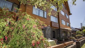 A hotel with a stone facade, wooden balconies, and outdoor seating.