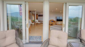 Un salón espacioso con televisor, asientos cómodos y vistas al exterior.