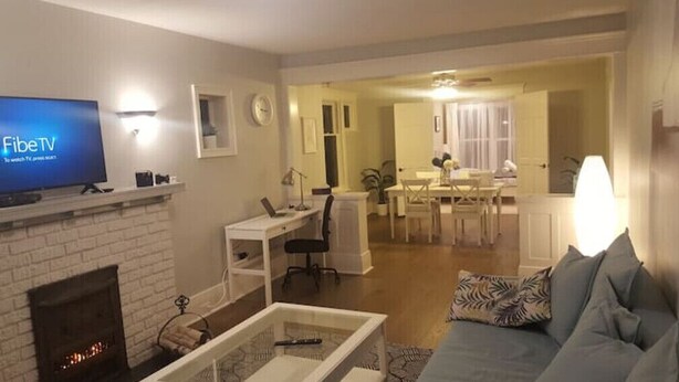 A living room with a fireplace, a television, a dining area, and a kitchen in the background. - Otylja Suite in Wortley Village (King Size Bed)
 (London)