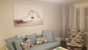 A living room with a sofa, a patterned armchair, a wall-mounted painting, and a window with curtains. - Otylja Suite in Wortley Village (King Size Bed)
 (London)