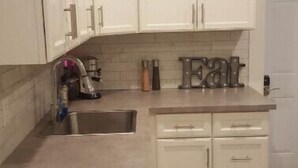 A kitchen with white cabinets, a sink, and a countertop with a coffee maker and salt and pepper shakers. - Otylja Suite in Wortley Village (King Size Bed)
 (London)