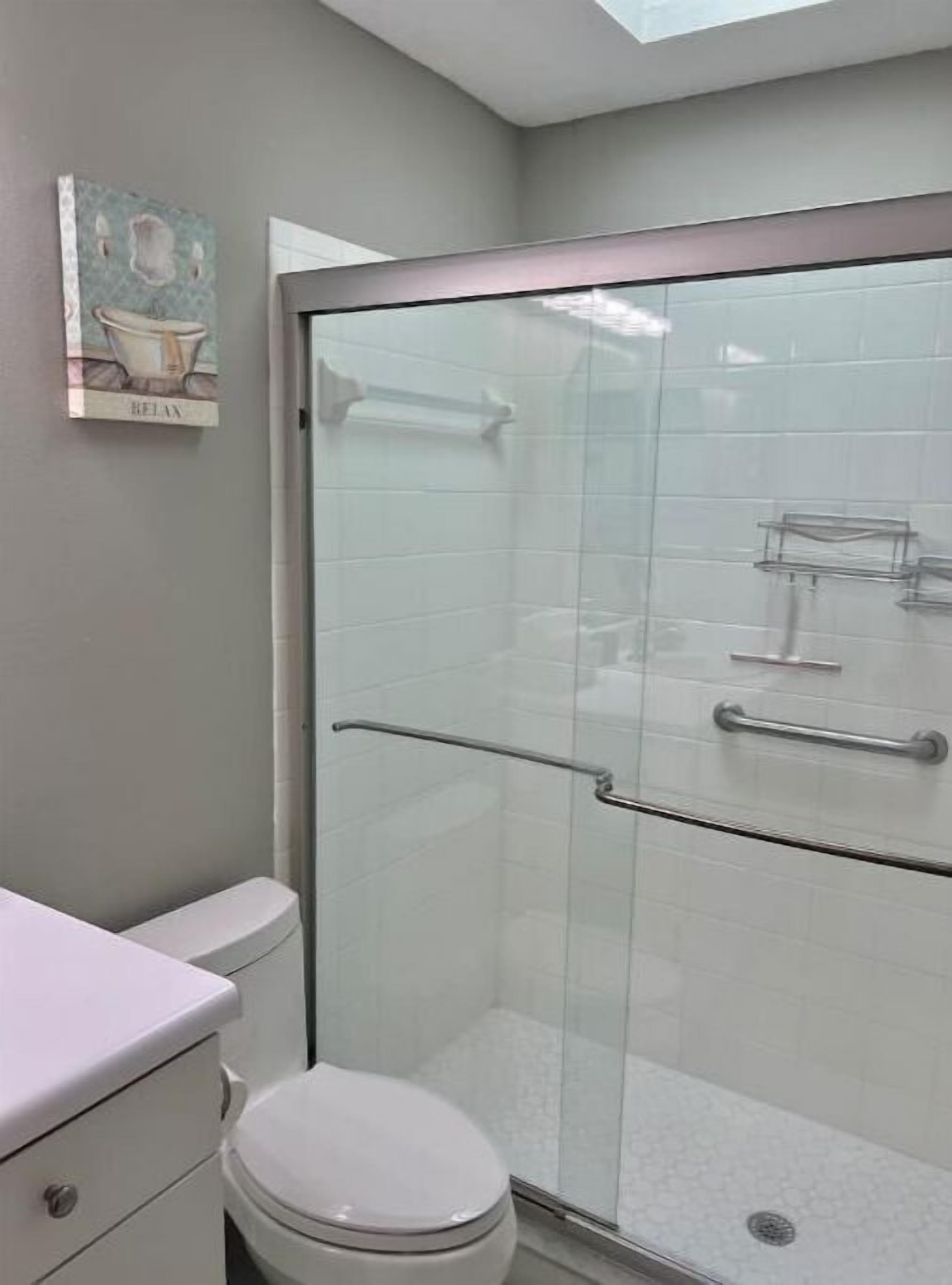 Une salle de bain moderne avec une douche à parois de verre, des toilettes blanches et un lavabo avec un plan de travail.