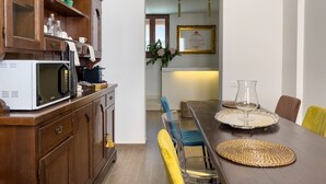 Un comedor con una mesa de madera, sillas amarillas y un microondas en la encimera.