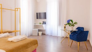 Una habitación de hotel con cama, escritorio, silla, televisor y candelabro.