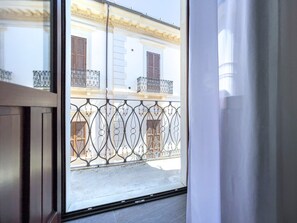 A view from a window with a metal balcony railing, a building with wooden shutters, and a clear sky. - Elegante e Raffinato B&B nel Pieno Centro Storico del L'aquila (L'Aquila)