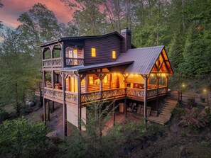A cabin with a balcony, a deck, and a staircase leading to the main entrance.