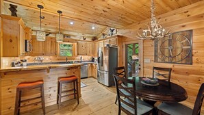 A wooden cabin interior with a kitchen, dining area, and a large clock on the wall. - Mountain Bliss Chalet (Blue Ridge)